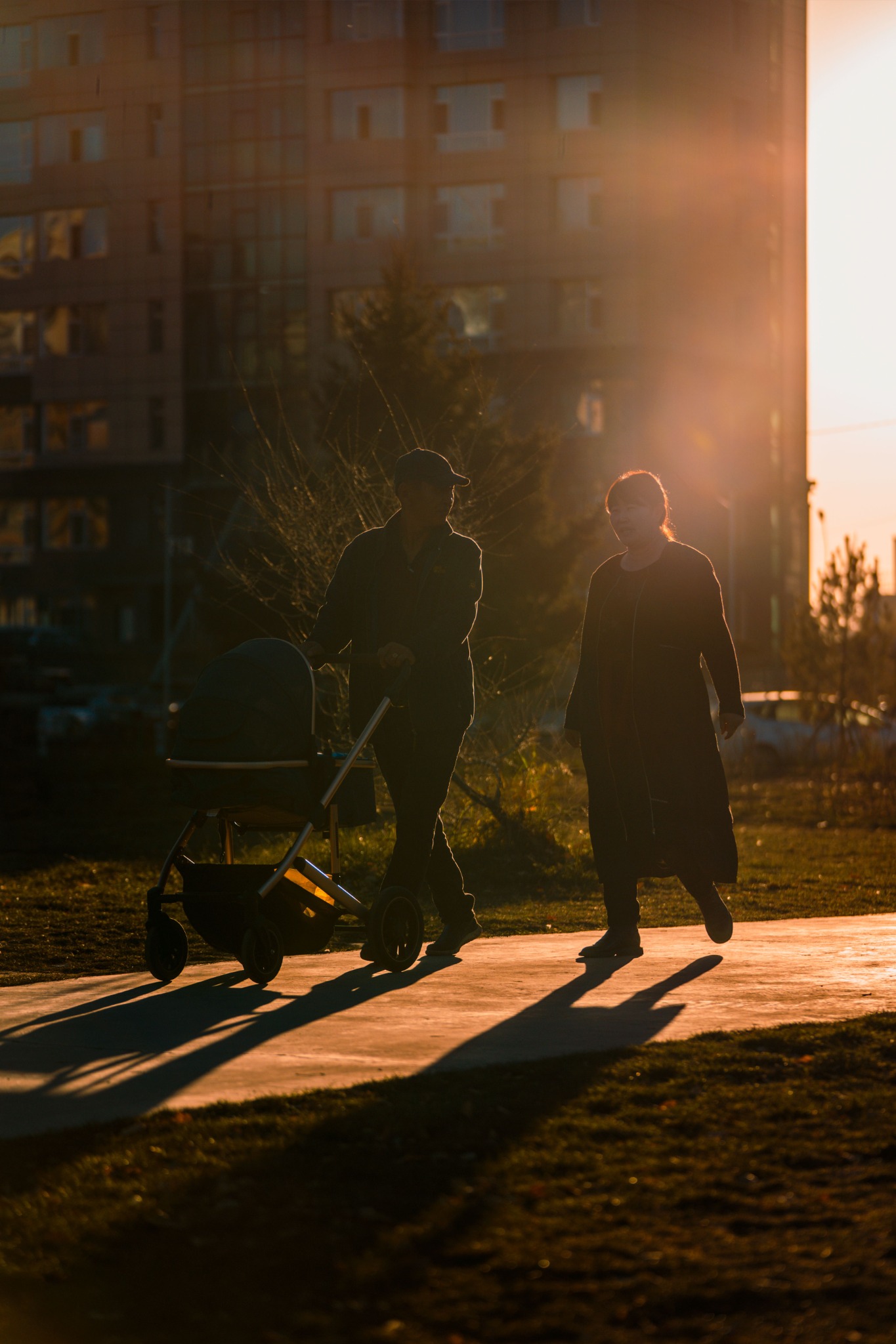 Concept imagery: People walking together with a stroller at sunset.